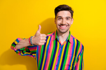 Portrait of positive guy in striped shirt thumb up symbol recommend follow his blog about man healthcare isolated on yellow color background