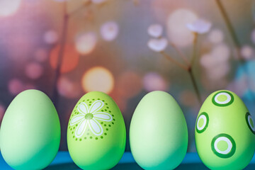 Front view of green Easter eggs on pastel blurred background, space for copy.