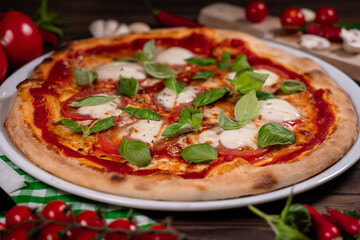 Caprese pizza tomatoes, mozzarella and basil on light wooden table