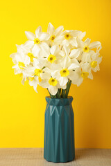 Spring easter background with daffodils bouquet in vase on yellow background. Vertical photo