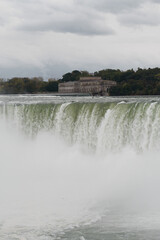 Fototapeta na wymiar Horseshoe waterfall in Niagara Falls and over it the building of Niagara Parks Power Station