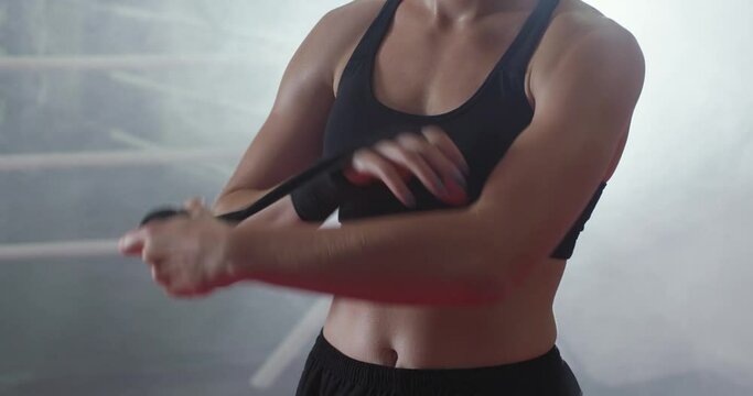 Anonymous woman fighter wraps her hands with boxing bandages, training day in a gym, the girl is preparing for battle.