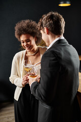 happy curly african american woman laughing near boyfriend while holding glass of wine during date