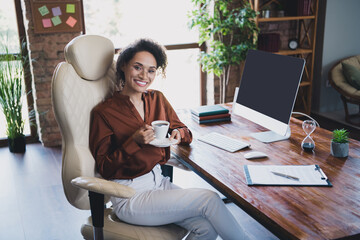 Photo of stunning positive company founder lady sitting chair hold aroma coffee cup workstation...