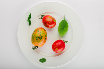 Fresh tomatoes and basil leaves in a white ceramic plate. - 693008170