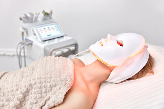 Woman lies with led light therapy facial mask in beauty salon