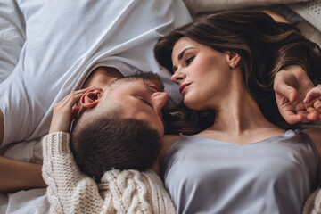 Beautiful happy loving young smiling couple relaxing in bed, looking at each other. Cozy home...