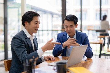 Two happy asian businessman talking and consulting working together with laptop computer  in the...