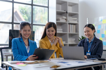 Asian businesswomen collaborate and discuss business plan during team meeting in modern office.