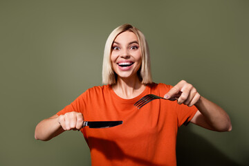 Photo of cheerful funny glad girl hold hands knife with fork grimacing hungry person enjoying her...