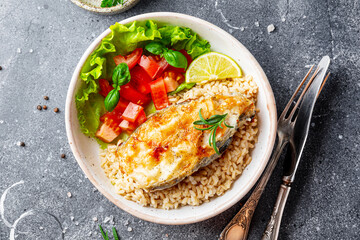 Fried catfish steak with rice and vegetable salad on a gray background top view