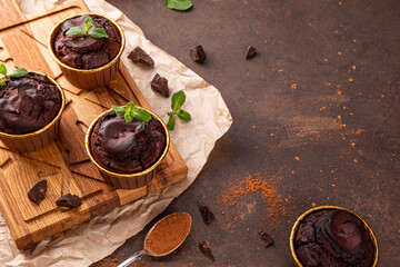 Chocolate brownie muffins with mint on dark background, copy space for text