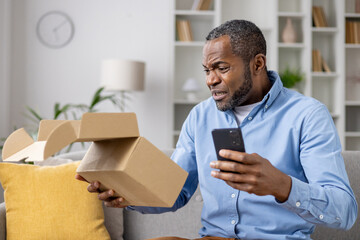 Dissatisfied sad online buyer, man received wrong damaged parcel, african american man sitting at...