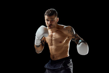 Concentrated serious young man, shirtless boxing athlete with strong muscular body fighting...