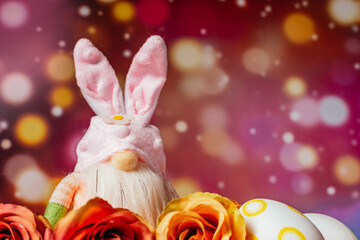 Colorful decorated Easter rabbit , eggs and flowers on pink background. Spring and Easter concept.