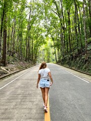 Youn girl walking around a autoroad in the middle of the forest in Bohol island, Philippines. High...