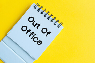 Out of office text on notepad with yellow background. Out of office concept