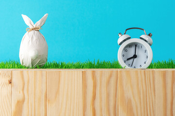 Easter egg wrapped in a paper in the shape of a bunny with alarm clock. Minimal Easter background....