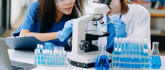 Two scientist or medical technician working, having a medical discuss meeting with an Asian senior female scientist supervisor in the laboratory with online reading, test sample