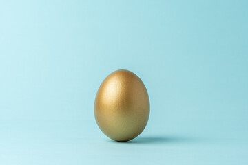 Golden Easter egg on blue background. Easter minimal concept. Creative Happy Easter or spring layout.