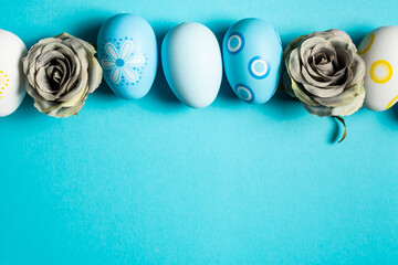 Decorated Easter eggs and gray flowers on light blue background. Greetings for Easter Day.
