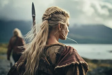 Fotobehang A Viking stands poised and resolute on the battlefield, her intricate braids and battle-worn armor embodying the fierce spirit of the legendary female warriors of Norse mythology © ChaoticMind