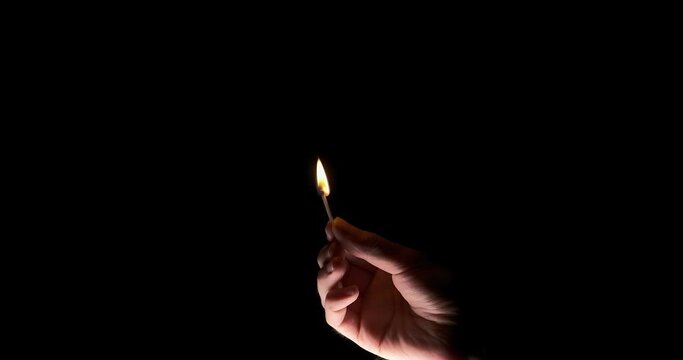 Lighting a match in hand on a black background