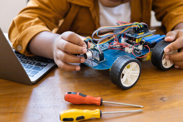 An Asian boy is building a metal robot and a programmable electr