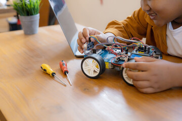 An Asian boy is building a metal robot and a programmable electr