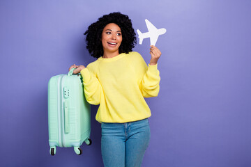Photo of positive woman with afro hairdo dressed sweater look at little plane in arm holding...