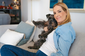 Young woman with her cute Schnauzer dog at home. Lovely pet