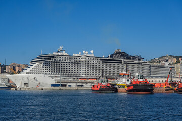 Big modern cruiseship or cruise ship liner Seaside Seaview in port with downtown Genoa skyline in...