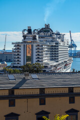 Big modern cruiseship or cruise ship liner Seaside Seaview in port with downtown Genoa skyline in...