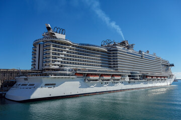Big modern cruiseship or cruise ship liner Seaside Seaview in port with downtown Genoa skyline in...