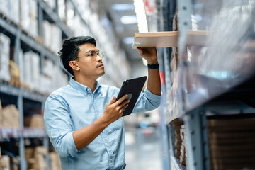 Businessman or supervisor uses a digital tablet to check the stock inventory in furniture large warehouses, a Smart warehouse management system, supply chain and logistic network technology concept. - obrazy, fototapety, plakaty