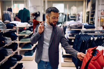 Young happy man buying vest at clothing store.
