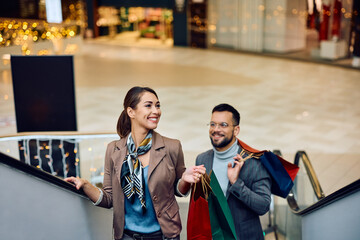 Young smiling couple on escalator in shopping mall.