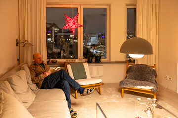 Stockholm, Sweden A man relaxes in her couch at home in the living room under Christmas ornaments.