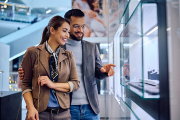 Young happy couple choosing jewelry in store at shopping mall.