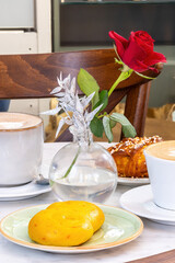 Stockholm, Sweden A cozy cafe table with a rose for a Swedish fika or coffee and sweet cinnamon bun.