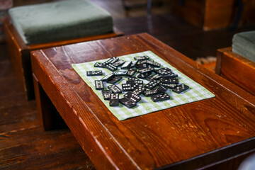 Figures of the game of dominoes scattered on a small tablecloth on a small table in the living room