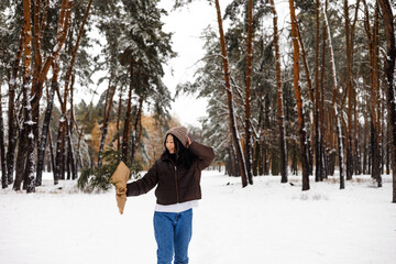 Fototapeta na wymiar Young Asian woman holding Christmas tree branch enjoying winter weather in the snow forest. holidays, rest, travel concept.