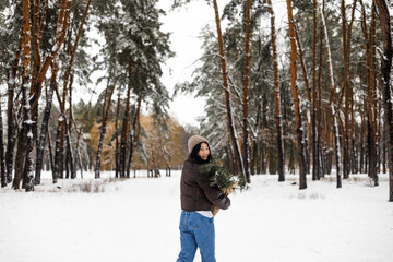 Fototapeta na wymiar Young Asian woman holding Christmas tree branch enjoying winter weather in the snow forest. holidays, rest, travel concept.