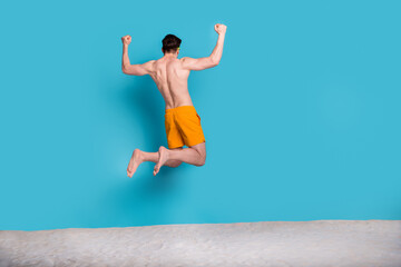 Full length photo of nice young male jump raise fists celebrate wear trendy yellow shorts isolated...