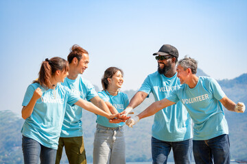 group of diverse ethnicity volunteers smiling,stacked hands together gesture of engage in some sort of teamwork activity, joining forces together to work for society