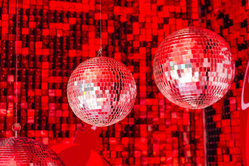 Mirror disco balls suspended in a club among shiny red mosaic in the shape of squares, disco...