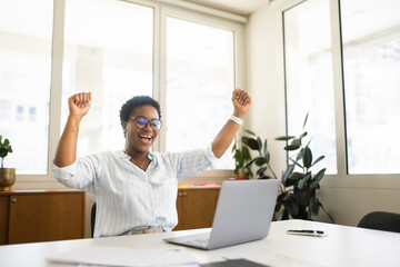 Excited African-American female freelancer raising hands in ecstatic, business woman got promotion,...
