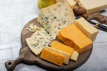 English cheeses collection, mature and coloured cheddar cheese and semi-soft, crumbly old stilton blue cheese close up