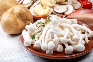 Ingredients for dinner dish with potato and mushrooms with onion. White shimeji edible mushrooms native to East Asia, buna-shimeji is widely cultivated