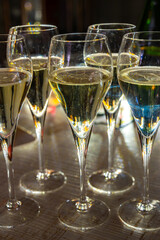 New year party, small bubbles of brut champagne cava or prosecco wine in tulip glasses with garland  lights on background